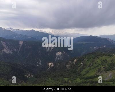 La vue aérienne du Grand Caucase en Géorgie montre des crêtes stratifiées, des falaises calcaires, des vallées boisées et des prairies alpines sous des nuages bas et diffus l Banque D'Images