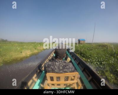 Un homme assis sur un bateau étroit dans le lac Inle au Myanmar Banque D'Images