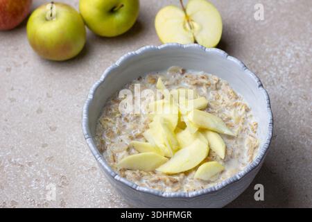 Bouillie de céréales multigrains à base de seigle, d'avoine, d'orge, de sarrasin et de flocons de blé, servie avec du lait et des tranches de pommes fraîches. Fond de pierre neutre Banque D'Images