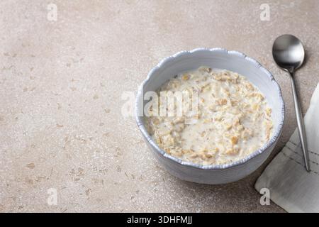 Bouillie de céréales multigrains fabriquée à partir de flocons de céréales mélangés, y compris le seigle, l'avoine, l'orge, le sarrasin et le blé. Scène de petit déjeuner minimal avec du lait, doux Banque D'Images