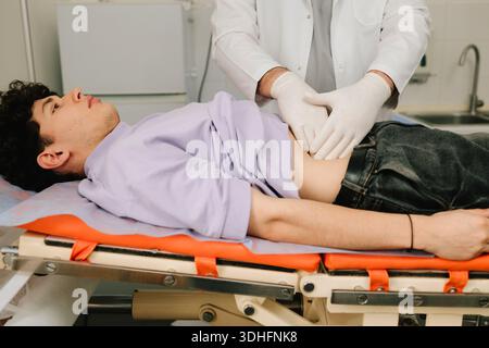 Urologue examine les reins masculins couchés sur le dos pour la taille de la douleur ou l'inflammation Banque D'Images