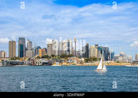 Yacht voyageant avec le paysage urbain du quartier des affaires de Sydney en arrière-plan. Banque D'Images