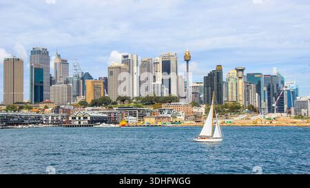 Yacht voyageant avec le paysage urbain du quartier des affaires de Sydney en arrière-plan. Banque D'Images