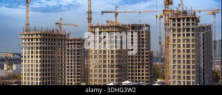 Vue frontale de plusieurs immeubles résidentiels de grande hauteur en construction avec grues à tour en environnement urbain. Capturé en haute résolution 7K sur Banque D'Images