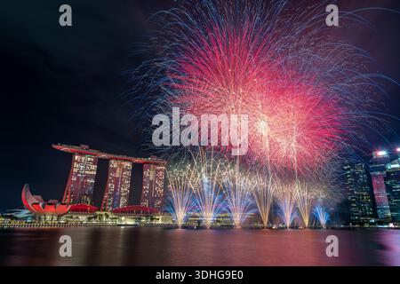 Des feux d'artifice illuminent Marina Bay Sands et les gratte-ciel de Singapour lors d'une célébration festive de la fête nationale en soirée. Banque D'Images
