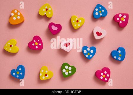 Une couche plate en forme de coeur coloré avec des motifs ludiques et des couleurs vives, soigneusement disposés sur un fond rose doux. Banque D'Images