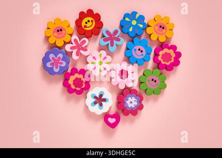 Un motif à plat en forme de coeur vibrant avec une collection de décorations colorées en forme de fleurs, de visages souriants et en forme de coeur Banque D'Images