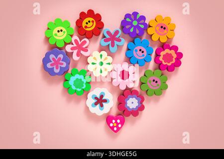 Un motif à plat en forme de coeur vibrant avec une collection de décorations colorées en forme de fleurs, de visages souriants et en forme de coeur Banque D'Images