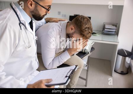 Jeune médecin empathique apaisant le patient de confort cachant la face dans les paumes Banque D'Images