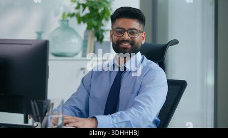 Heureux souriant arabe ethnique musulman homme d'affaires indien homme d'affaires tapant ordinateur joyeux avec le travail en ligne regardant la caméra sourire positif insouciant Banque D'Images