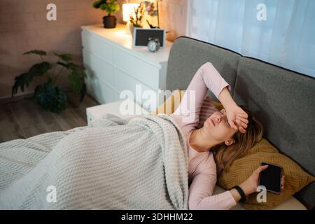 Femme ayant mal à la tête après une nuit sans sommeil dans la chambre Banque D'Images