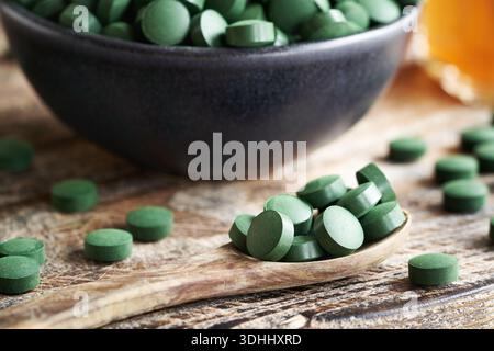 Comprimés d'algues spiruline sur une cuillère en bois et dans un bol sur une table Banque D'Images