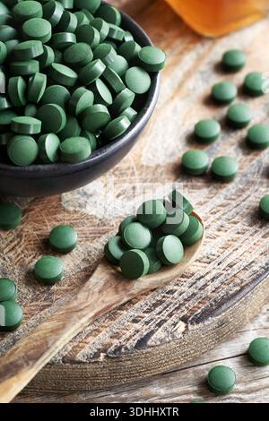 Comprimés d'algues spiruline ou pilules sur une cuillère en bois Banque D'Images