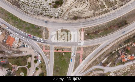 Vue aérienne symétrique de haut en bas d'un rond-point moderne et intersection avec des voitures en mouvement et des îles verdoyantes. Banque D'Images