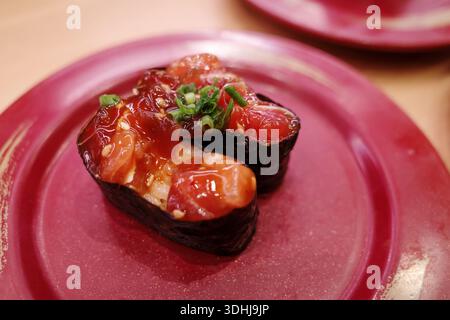 Gros plan au-dessus de deux morceaux de sushi Gunkan maki remplis de thon épicé mariné et garni d'oignons verts hachés. Banque D'Images