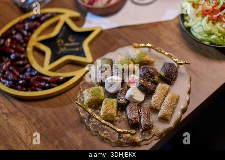 La famille profite de l'iftar ensemble dans un restaurant orné de décorations Ramadan. Ils partagent des plats traditionnels tout en rompant le jeûne pendant le mois sacré. Banque D'Images