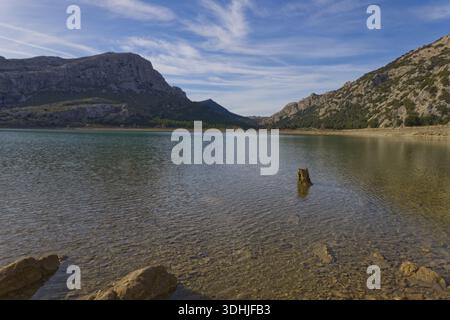 Pierres sur le rivage du réservoir Cúber dans les montagnes de la Serra de Tramuntana, Majorque, sous un ciel bleu avec des nuages. Banque D'Images