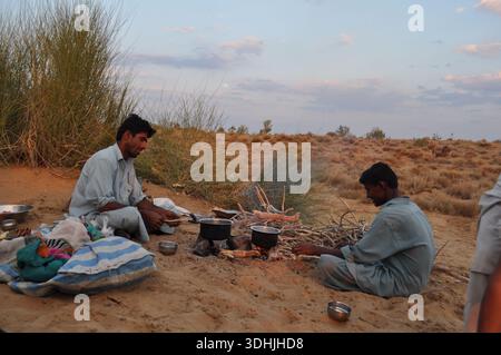 Les hommes préparent de la nourriture à côté d'un feu de camp dans le désert, Rajasthan, Inde Banque D'Images