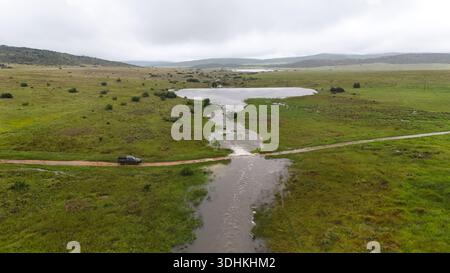 Vue aérienne d'un paysage où un ruisseau coule à travers un champ et sur un chemin de terre, Vaalwater, Limpopo, Afrique du Sud. Banque D'Images