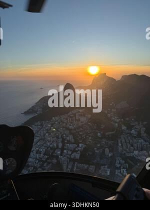 Coucher de soleil aérien sur les montagnes côtières et la ville dense d'un hélicoptère, lumière de l'heure d'or spectaculaire. Banque D'Images
