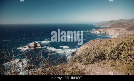 Une vue panoramique sur les falaises côtières escarpées surplombant le vaste océan bleu profond. La scène capture la beauté naturelle du littoral avec Waves cra Banque D'Images