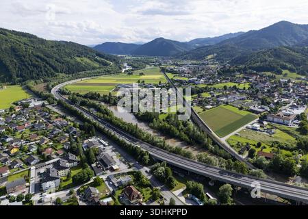 Vue aérienne de la rivière mur serpentant à travers la vallée, contrastant avec les lignes droites de l'autoroute et les montagnes verdoyantes, Peggau-Deuts Banque D'Images