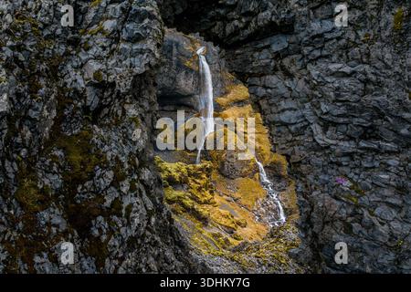 Vue aérienne d'une cascade délicate descendant en cascade des falaises accidentées, des taches moussues accrochées aux rochers, un joyau caché dans la beauté sauvage de l'Islande, Seljava Banque D'Images