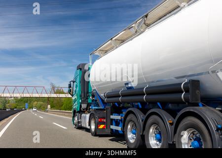 Blanc gros camion-citerne moderne cargaison semi-remorque commerciale se déplaçant rapidement sur autoroute ville banlieue urbaine. Logistique de distribution commerciale Banque D'Images