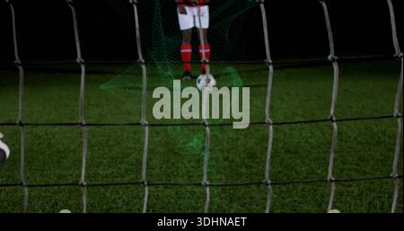 Positionnement du joueur aligné tir sur le terrain de football la nuit, filet, balle, short blanc, chaussettes rouges Banque D'Images