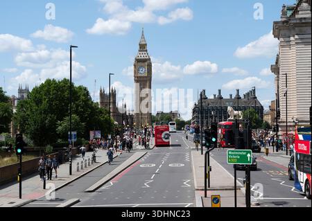 Big Ben (Elizabeth Tower) s'élève au-dessus d'une rue animée de Londres, au Royaume-Uni, remplie de bus à impériale rouges, de cyclistes et de piétons. Architecture historique Banque D'Images