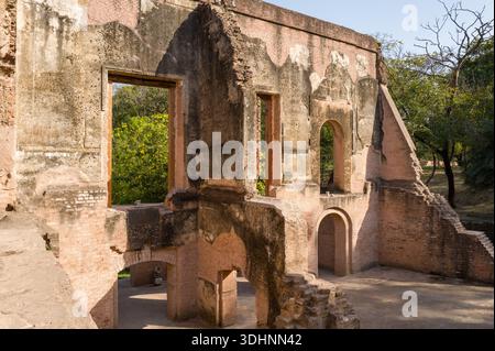 Lucknow, Inde - 15 mars 2024 : L'image montre les vestiges d'un bâtiment en briques avec de grandes ouvertures de fenêtres rectangulaires et voûtées, des murs partiellement effondrés et des espaces intérieurs visibles sur le site de la maison du Dr Fayrer dans le complexe de résidence, entouré d'arbres et de verdure à la lumière du jour. Banque D'Images