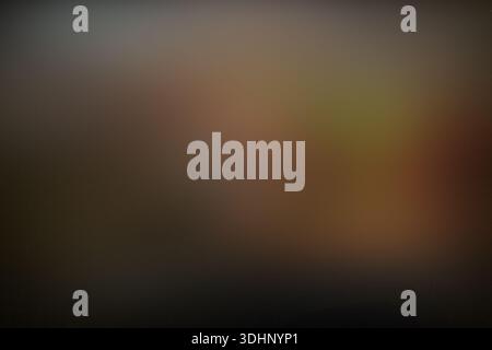 Fond sombre abstrait avec des flous bruns et oranges flous flous flous, avec une texture granuleuse pour une atmosphère cinématographique et morose. Banque D'Images