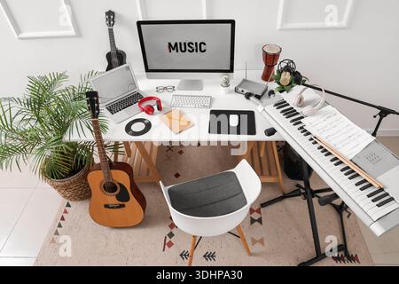 Lieu de travail avec ordinateur et instruments de musique près du mur de lumière dans le studio Banque D'Images