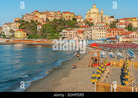 Vue sur la plage de Porto Maurizio à Imperia, Ligurie, Italie, avec rivage de sable, chaises longues et parasols, et la vieille ville historique s'élevant au-dessus. Banque D'Images