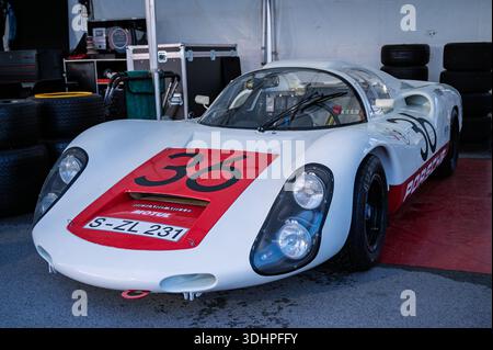 Vue de face d'une voiture de course Porsche 910 1967 blanche et rouge classique dans la voie des stands, préparée et prête à entrer sur la piste. Banque D'Images