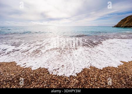 Mousse de mer blanche lavant sur Pebble Beach Banque D'Images
