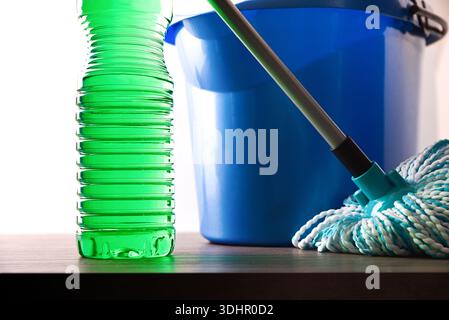 Nettoyage des sols avec des produits désinfectants dans une bouteille en plastique avec du produit vert sur une surface en bois avec une serpillière et un seau de serpillière sur un blanc isolé b Banque D'Images