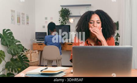 Équipe jeune diversifiée dans Bright Startup Office, femme Yawning à Laptop Banque D'Images