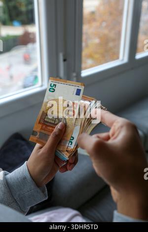 Une liasse de billets de 50 euros tenue par la main d'une femme afro-américaine Banque D'Images