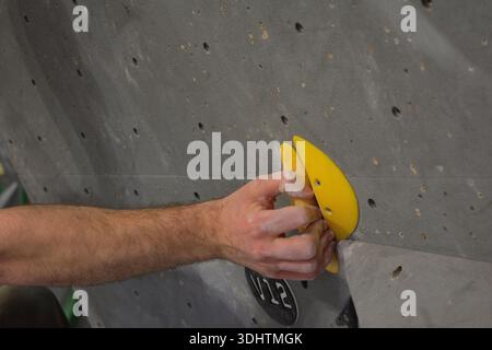 Main craie saisissant une cale jaune V12 sur un mur intérieur de Boulding Banque D'Images