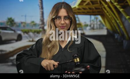 Une femme juge portant une robe frange un marteau en bois sur un bloc sonore dans la zone extérieure d'entrée du terminal de l'aéroport ; discipline d'équité de l'autorité judiciaire. Banque D'Images