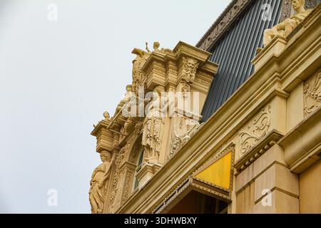 Vue en bas angle de sculptures et sculptures en pierre classiques détaillées sur une façade de bâtiment historique contre un ciel couvert, architecture européenne. Banque D'Images