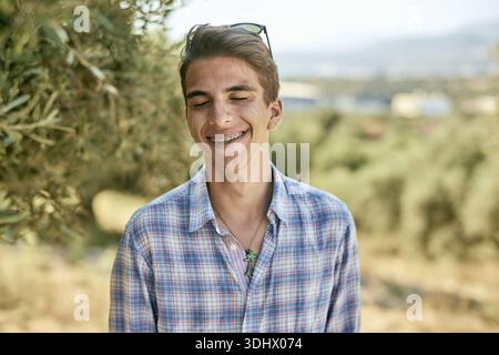 Adolescence, portrait d'un jeune homme joyeux avec des dentelles portant une chemise à carreaux et souriant les yeux fermés, insouciant, insouciant, sans souci, facilité, jeunesse, holi Banque D'Images