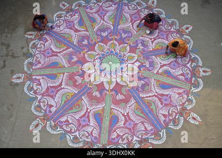 Agartala, Tripura, Inde, 12-01-2026 : des femmes peignent Alpona, sur le terrain avant le festival hindou Makar Sankranti dans le village de Lankamura à Agartala. Banque D'Images