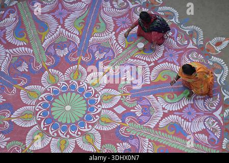 Agartala, Tripura, Inde, 12-01-2026:des femmes peignent Alpona, sur le terrain avant le festival hindou Makar Sankranti dans le village de Lankamura à Agartala. P Banque D'Images