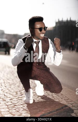 Homme excité dans des lunettes de soleil célébrant avec les poings serrés dans la rue, se sentant réussi, exalté, opportunités, opportunité, excitation, objectifs, celebr Banque D'Images