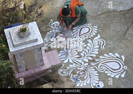 Agartala, Tripura, Inde, 12-01-2026 : des femmes peignent Alpona, sur le terrain avant le festival hindou Makar Sankranti dans le village de Lankamura à Agartala. Banque D'Images