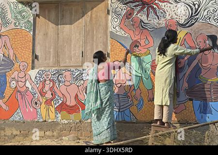 Agartala, Tripura, Inde, 12-01-2026 : des femmes peignent Alpona, sur le terrain avant le festival hindou Makar Sankranti dans le village de Lankamura à Agartala. Banque D'Images