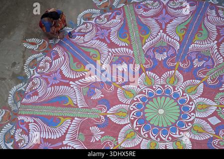 Agartala, Tripura, Inde, 12-01-2026 : des femmes peignent Alpona, sur le terrain avant le festival hindou Makar Sankranti dans le village de Lankamura à Agartala. Banque D'Images