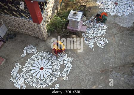 Agartala, Tripura, Inde, 12-01-2026 : des femmes peignent Alpona, sur le terrain avant le festival hindou Makar Sankranti dans le village de Lankamura à Agartala. Banque D'Images